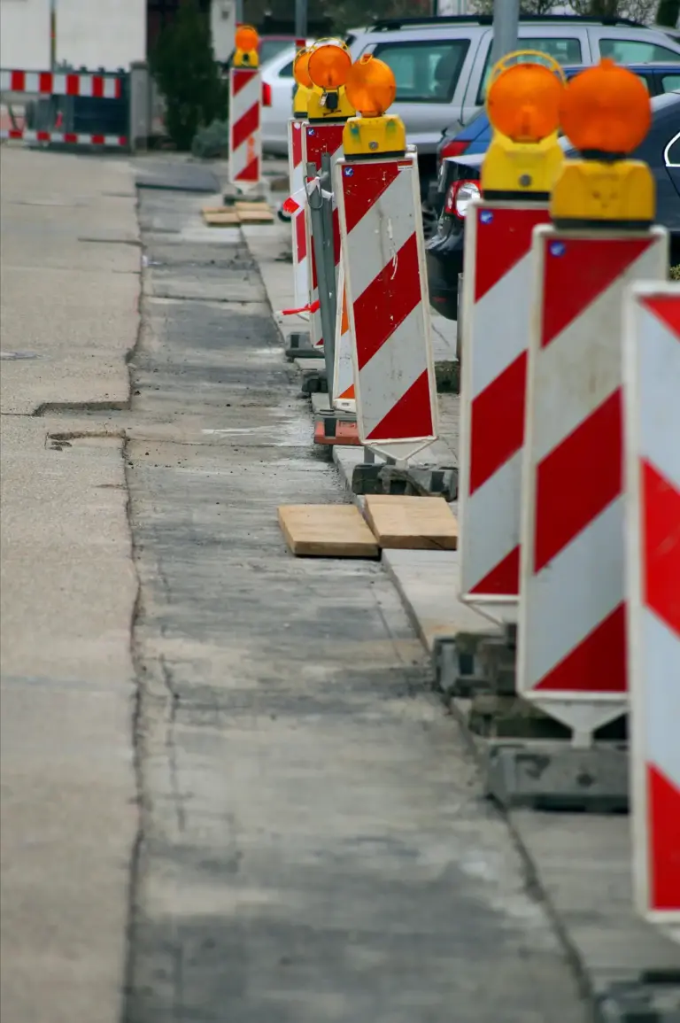 Absperrung einer Straßenbaustelle mit Warnleuchten und Holzblöcken für sichere Verkehrssicherung durch HashTEC.